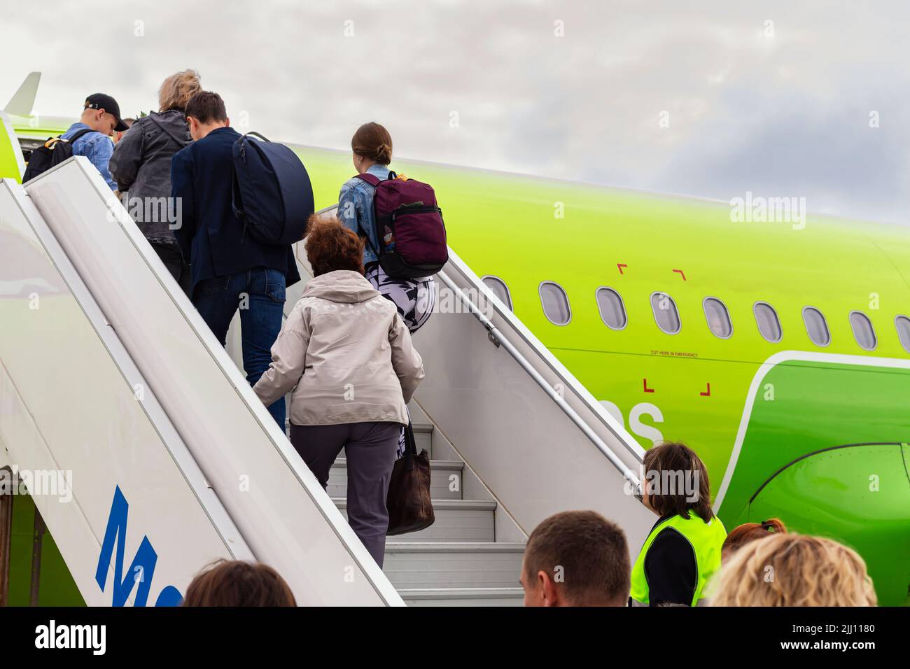 passengers with backpack travel in plane, rear view, selective focus. boarding airplane, people climbing ramp. transport and travel concept. using tec Stock Photo