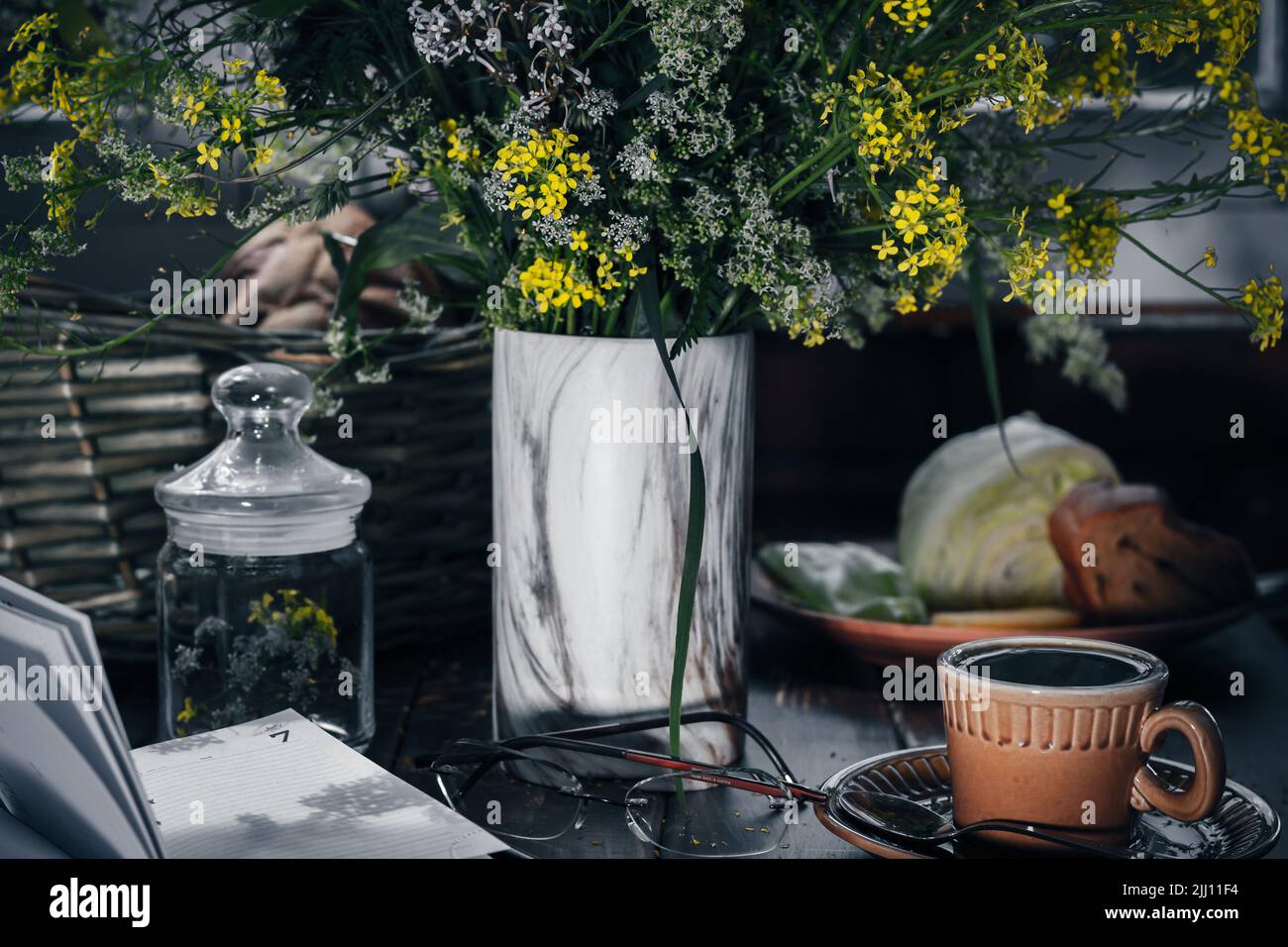 Twilight, tea drinking on veranda of country house, wild flowers on wooden table. insomnia concept. dark key, mental health.writing in pocketbook Stock Photo