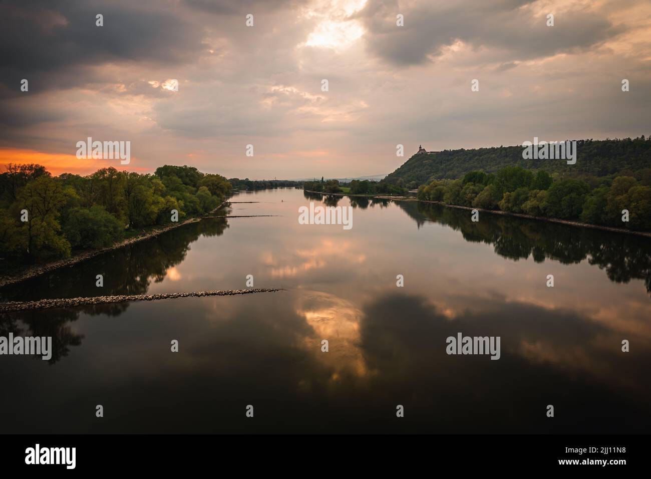 A beautiful view of a lake and a field with trees under the cloudy sky ...