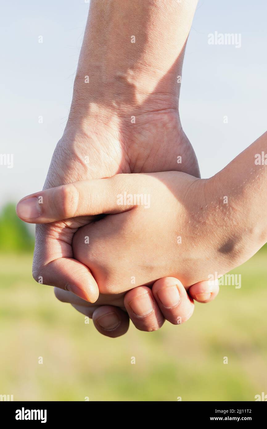 closeup Father holds daughter's hand on blurred nature background, outdoor. Trust, care and parenting family, father's day concept. hand of parent and Stock Photo