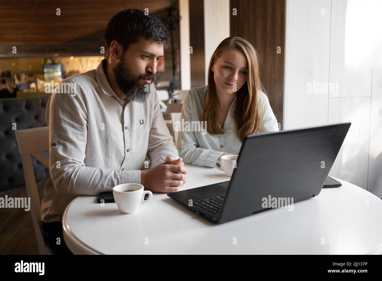 Happy young couple working in cafe using laptop, wireless internet for work, happy time together enjoyment, remote work concept Stock Photo