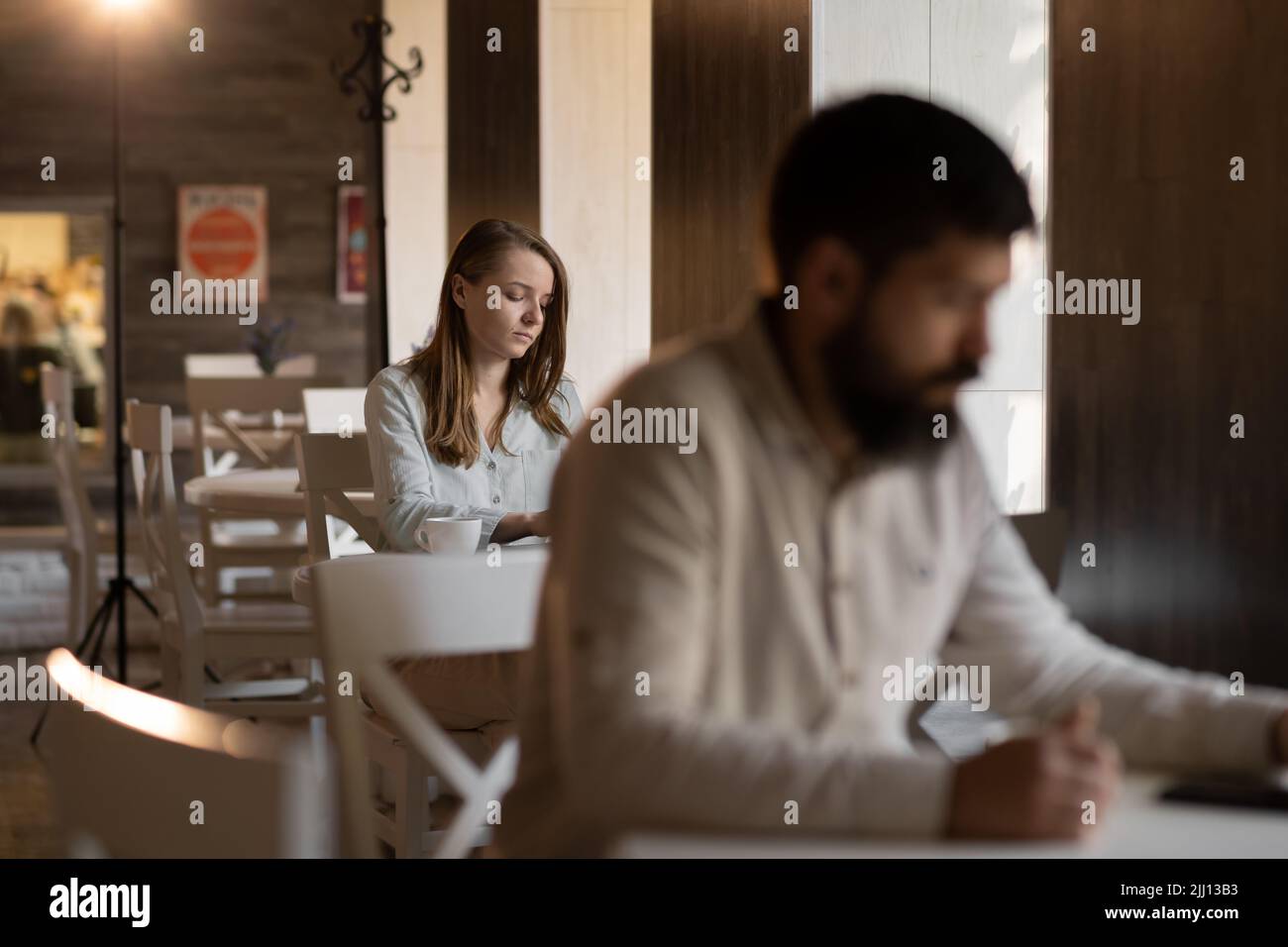 Young curious girl loves a bearded man looks with interest at a guy sitting next to him in a cafe, flirting in a public place, dating and love at firs Stock Photo