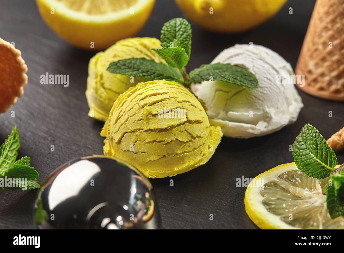 https://c8.alamy.com/comp/2JJ13WY/tasty-creamy-and-lemon-ice-cream-decorated-with-mint-served-on-a-stone-slate-over-a-black-background-2JJ13WY.jpg