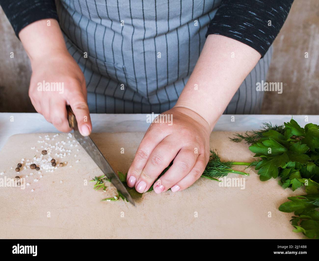 Cook chopping potherbs on wooden cutting board Stock Photo