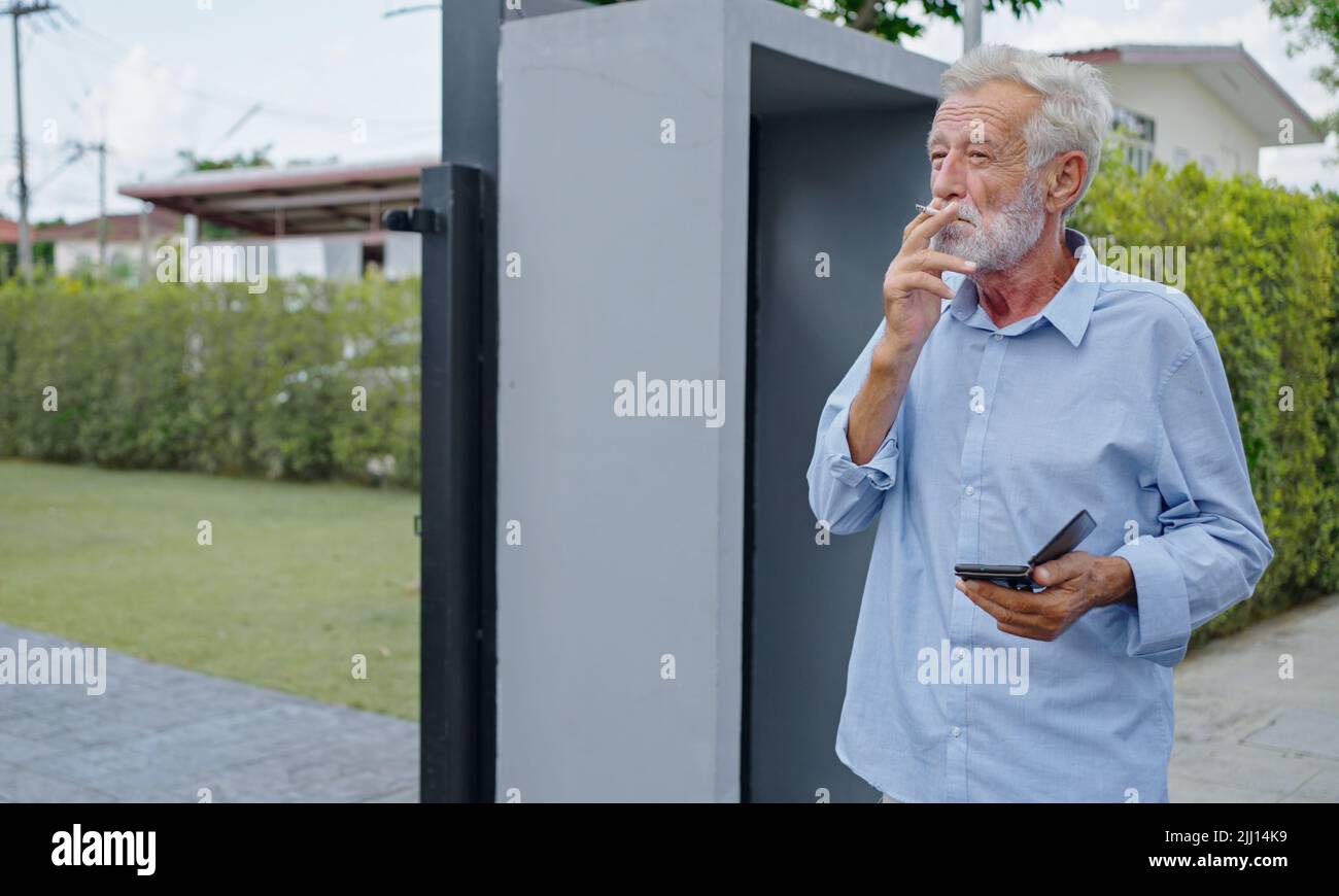 An old senior man smoking cigarette outside, smoke addiction, bad habbit. Stock Photo