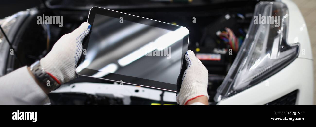 Mechanic use tablet device with black screen in front of car. Stock Photo