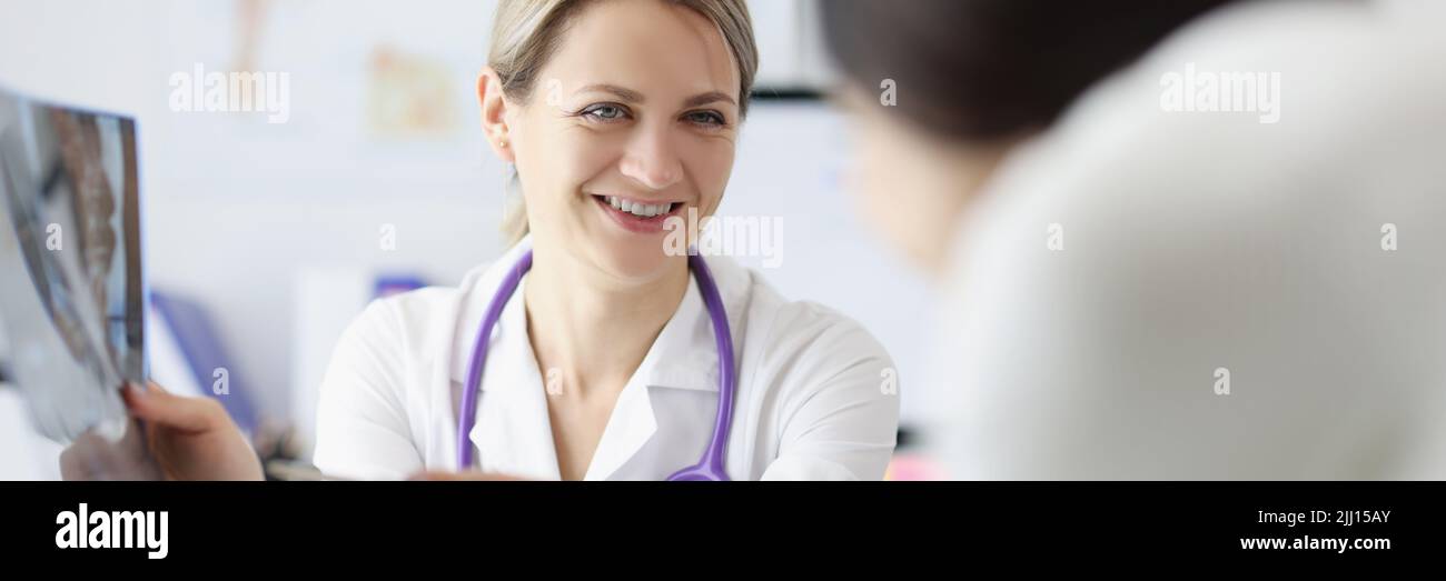 Female doctor show x ray result to patient and explain, professional specialist joking about