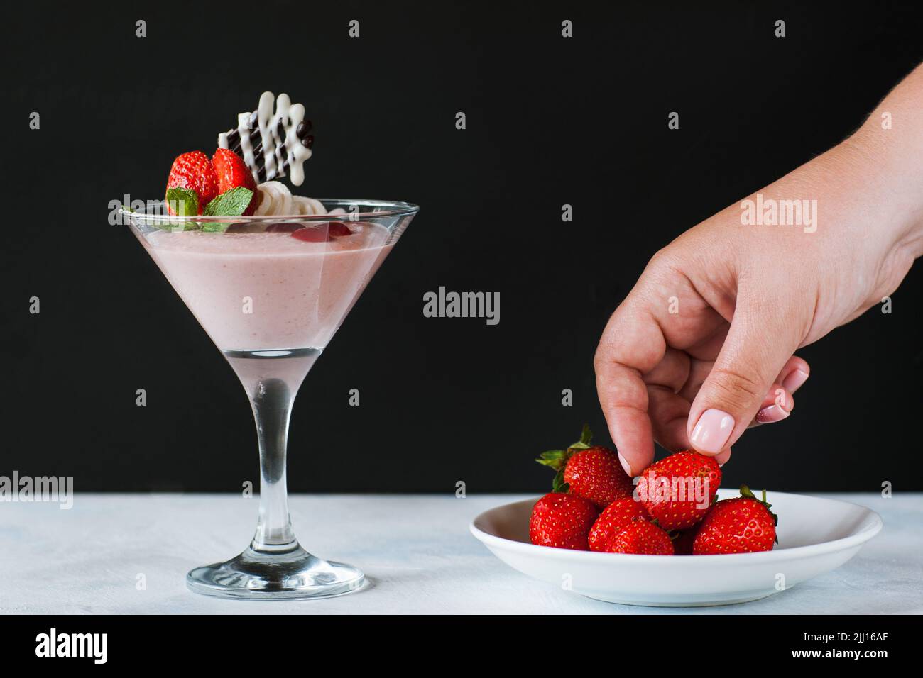 Young woman taking strawberry from little saucer Stock Photo