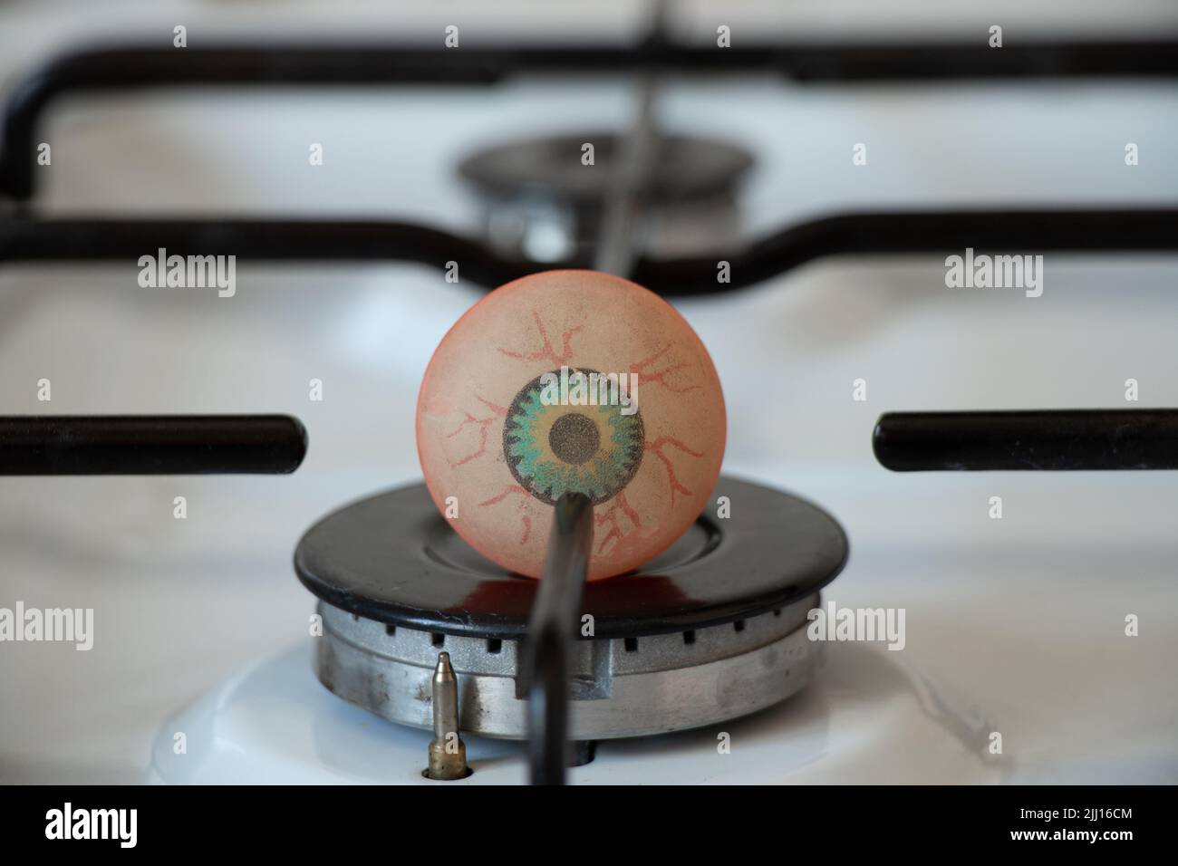 A ball with a drawn eye lies on a gas burner in the kitchen, I look and
