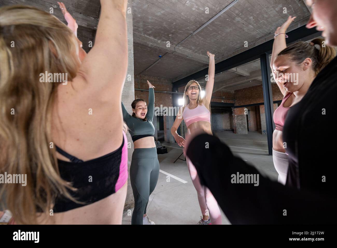 Group or team of happy young sportive women in a gym all cheering with elbows and applauding, all wearing facemasks to protect for coronavirus or covid. High quality FullHD footage Stock Photo