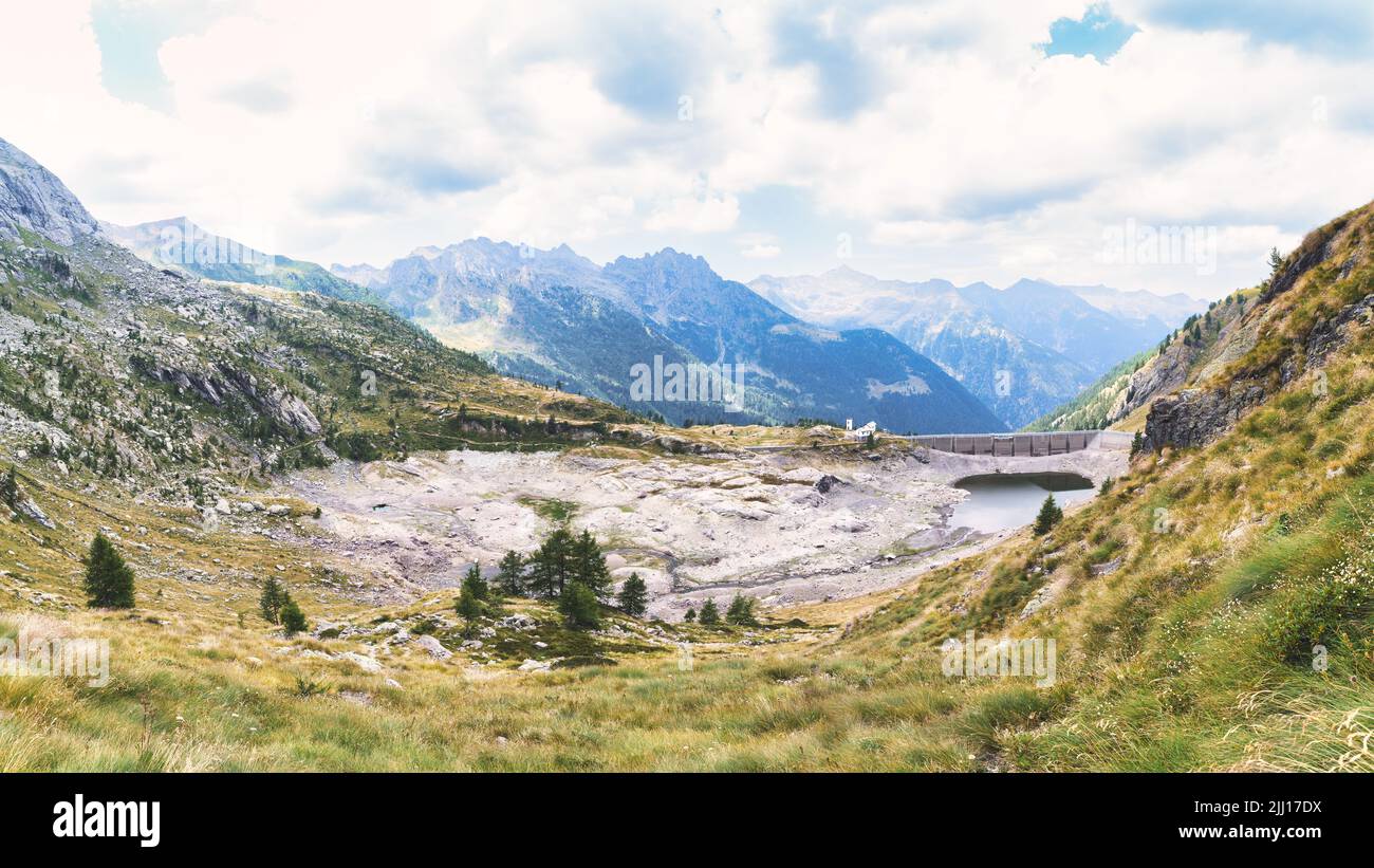 Dam in Lombardy Alps in Italy with artificial lake dried up by drought Stock Photo