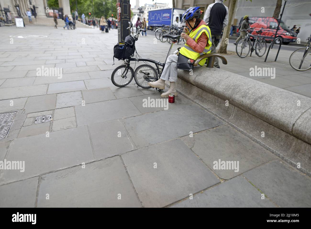 London, England, UK. Female cyclist stopping for a hot snack in St Martin's Lane by Trafalgar Square Stock Photo