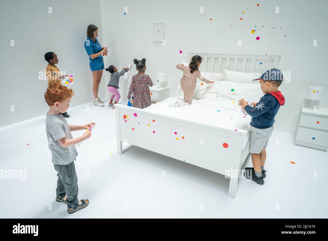 Children apply the first stickers to Yayoi Kusama's interactive work The obliteration room at the Tate Modern in London, which begins as a blank white apartment filled with all white furniture. Visitors are given a sticker sheet of colourful dots as they enter to turn the installation into a sea of colour. Picture date: Friday July 22, 2022. Stock Photo