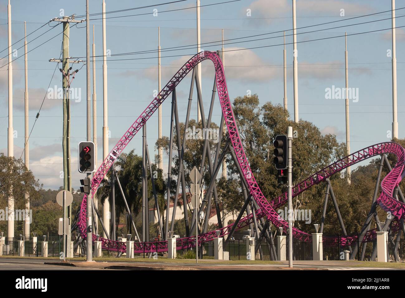 View from public road of Warner Brothers Movie World purple Hypercoaster thrill ride. Traffic lights on Entertainment Drive, Oxenford, Queensland, Aus. Stock Photo