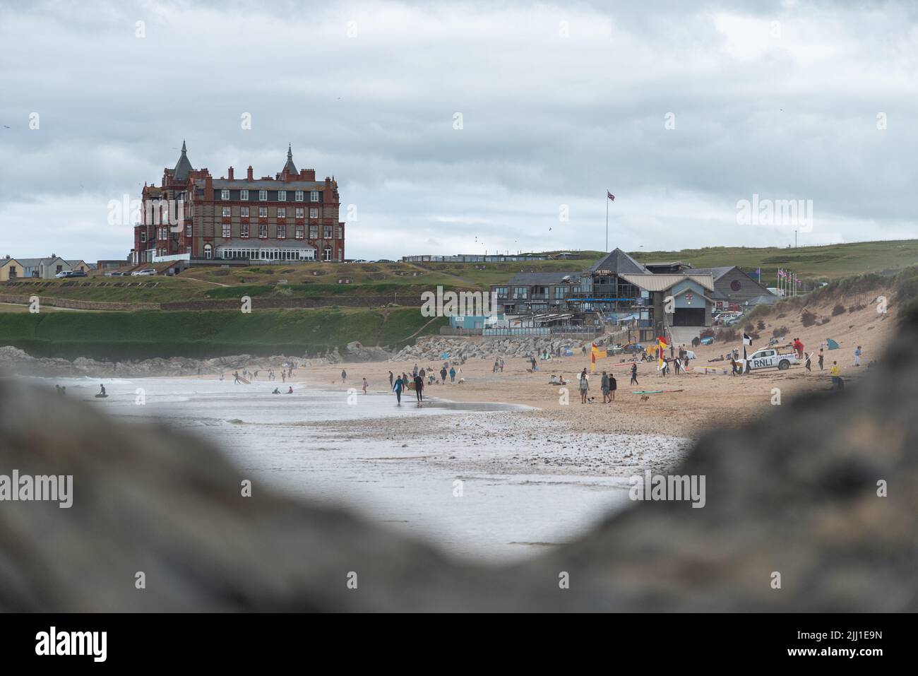 people surfing and swimming at Fistral Beach with the life guards watching and with The Headland Cornwall hotel in the background , Fistral Beach UK Stock Photo