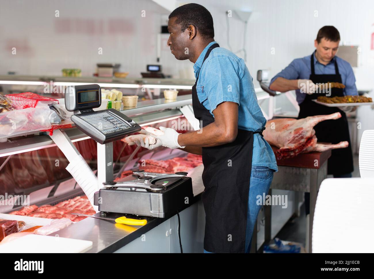 Successful owner of butcher store with his worker preparing fresh meat