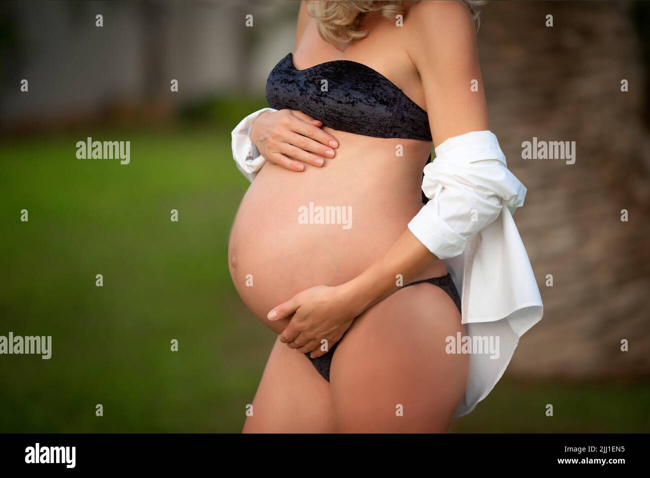 pregnant woman holds her stomach against the background of nature. Stock Photo