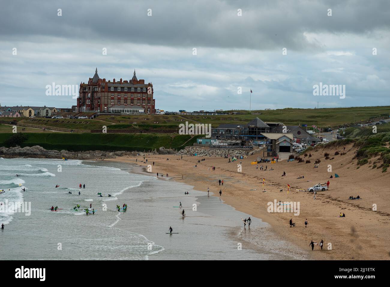 people learning to surf and swim at Fistral Beach and with The Headland Cornwall hotel in the background, Fistral Beach UK Stock Photo