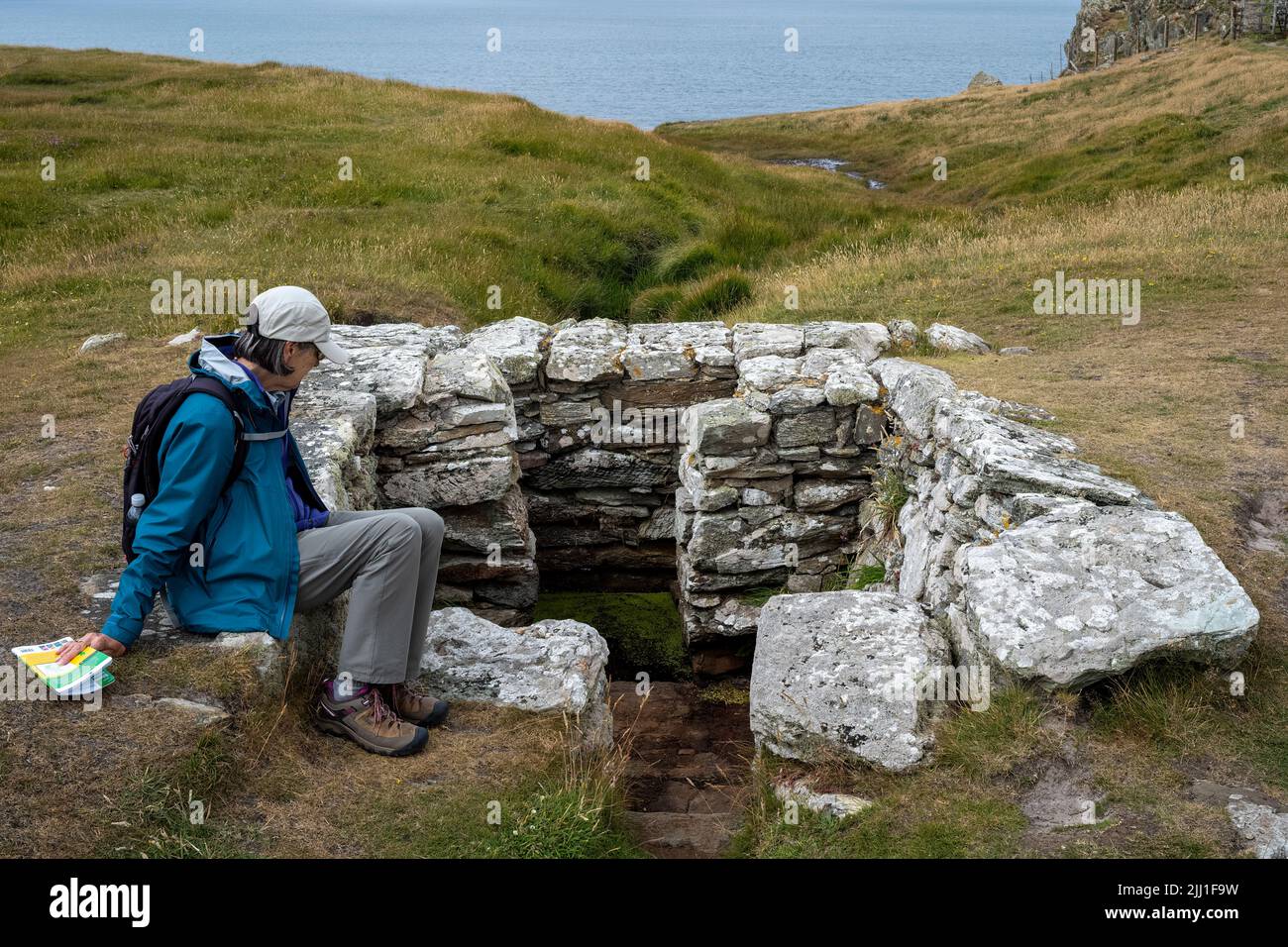 Pausing by the medieval construction around St Gwenfaens well, Rhoscolyn Head, Anglesey, Wales Stock Photo