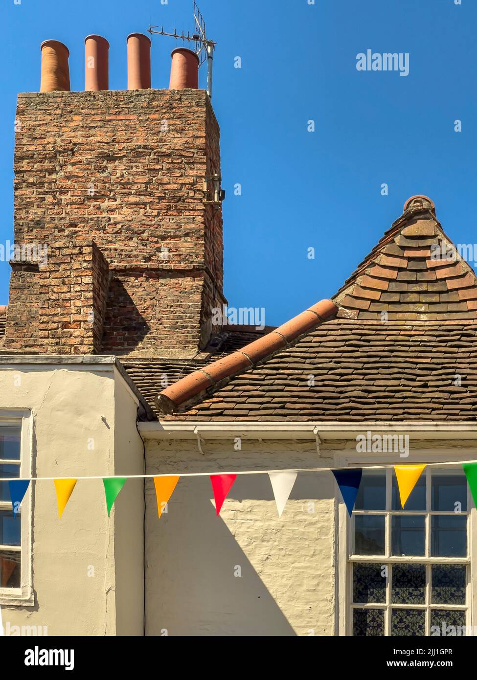 Old tiled rooftop in York city centre with coloured bunting, UK Stock Photo