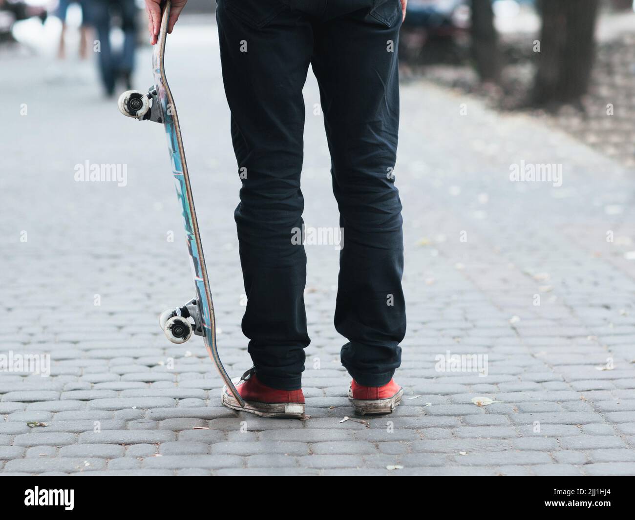 Skateboarder holding skate at street. Stock Photo
