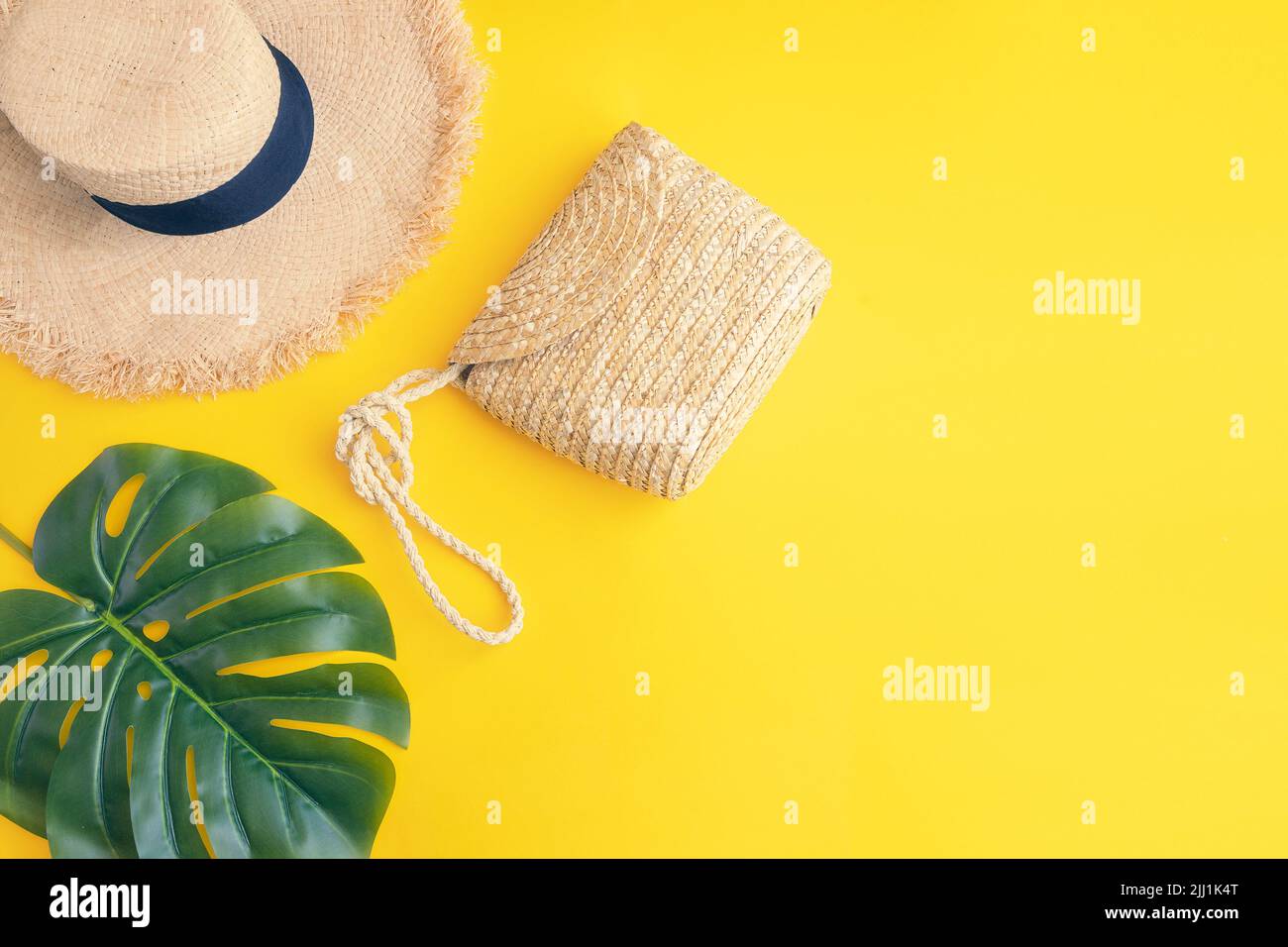 Tropical palm leaf, sun straw hat with straw bag on yellow background ...