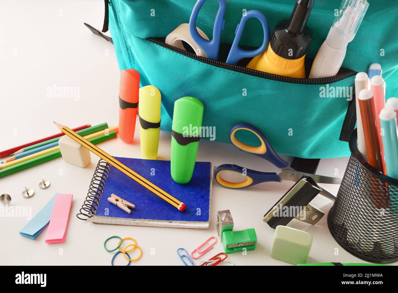 School supplies and blue backpack on white table. Elevated view. Horizontal composition. Stock Photo