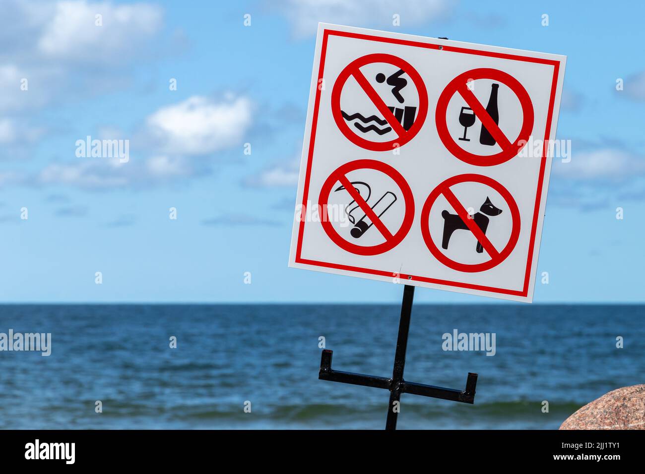 Beach rules signs are on a white banner mounted on a sea coast Stock Photo