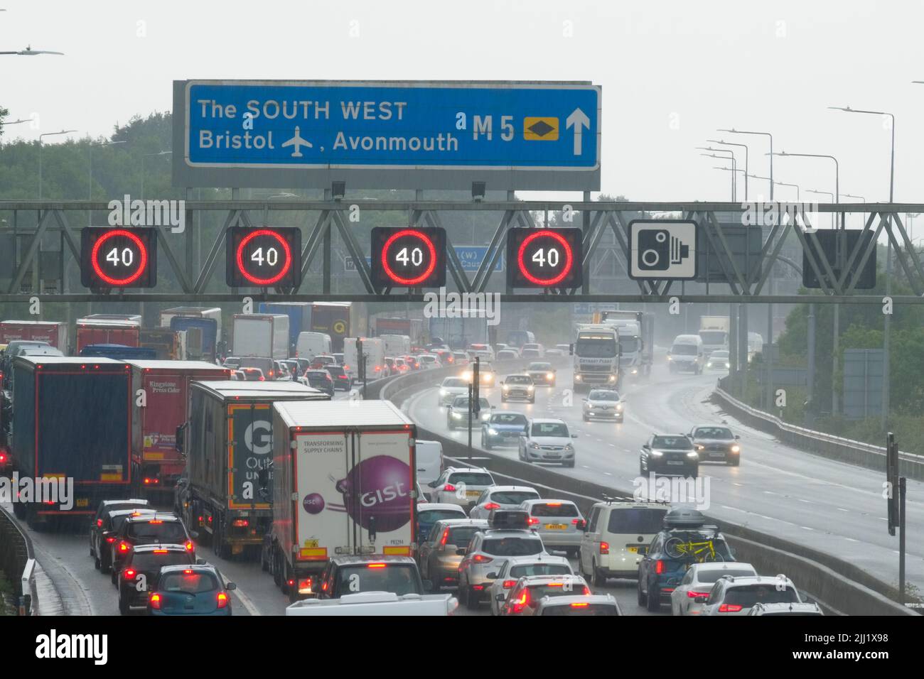Bristol, UK. 27th July, 2022. Sudden heavy showers break period of hot sunny weather. Heavy congestion on the M5 motorway as people head south as the schools break up; is made more frustrating by heavy showers. Managed motorway signs are on and Highways England show average speeds below 30MPH. Credit: JMF News/Alamy Live News Stock Photo
