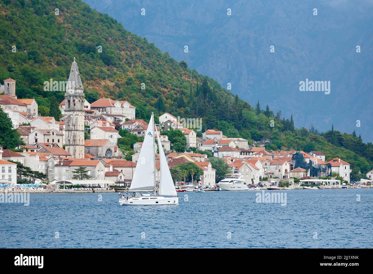 Sails yacht in sea against the backdrop of old seaside town. Stock Photo