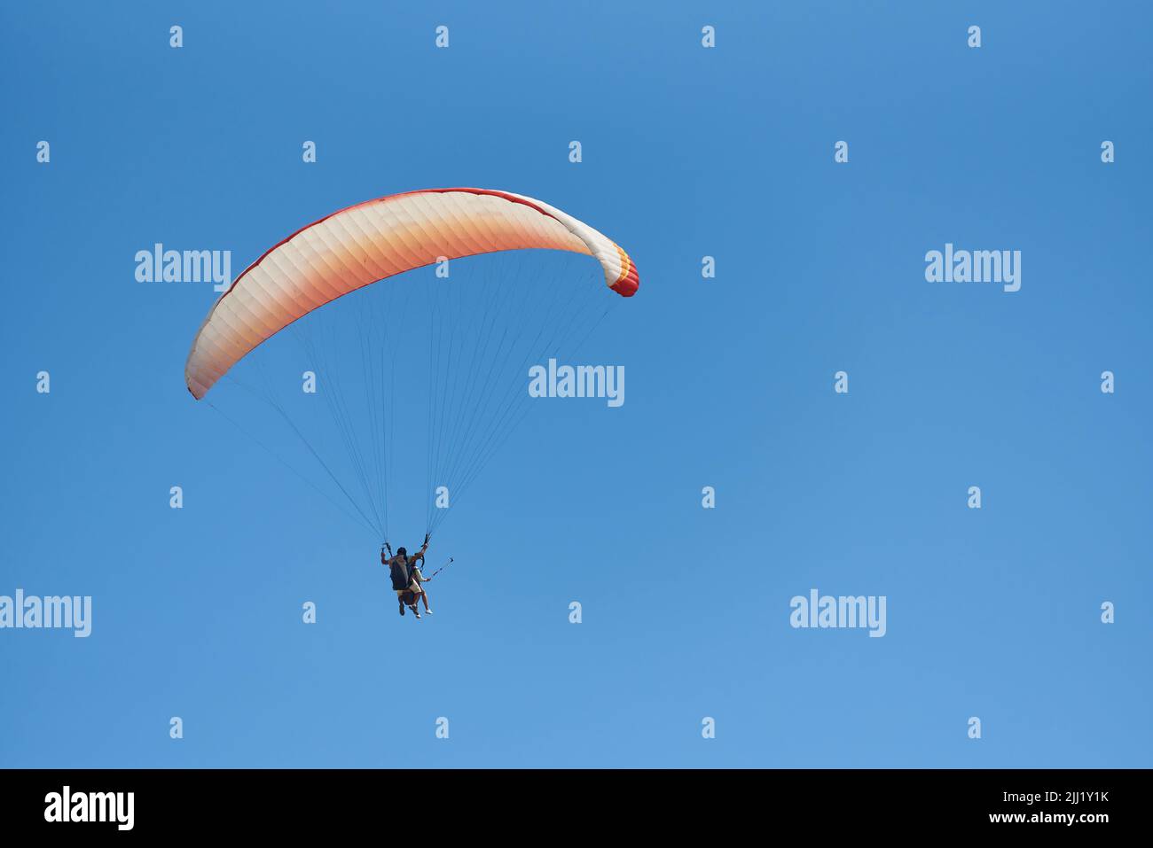Paragliding tandem with tourist in blue sky. Stock Photo