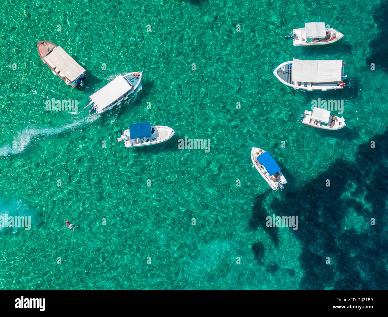 Aerial view of floating boats moored on a transparent sea. Relax on the Ionian Sea. Bathers. Corfu island, Limni beach Glyko. Greece Stock Photo