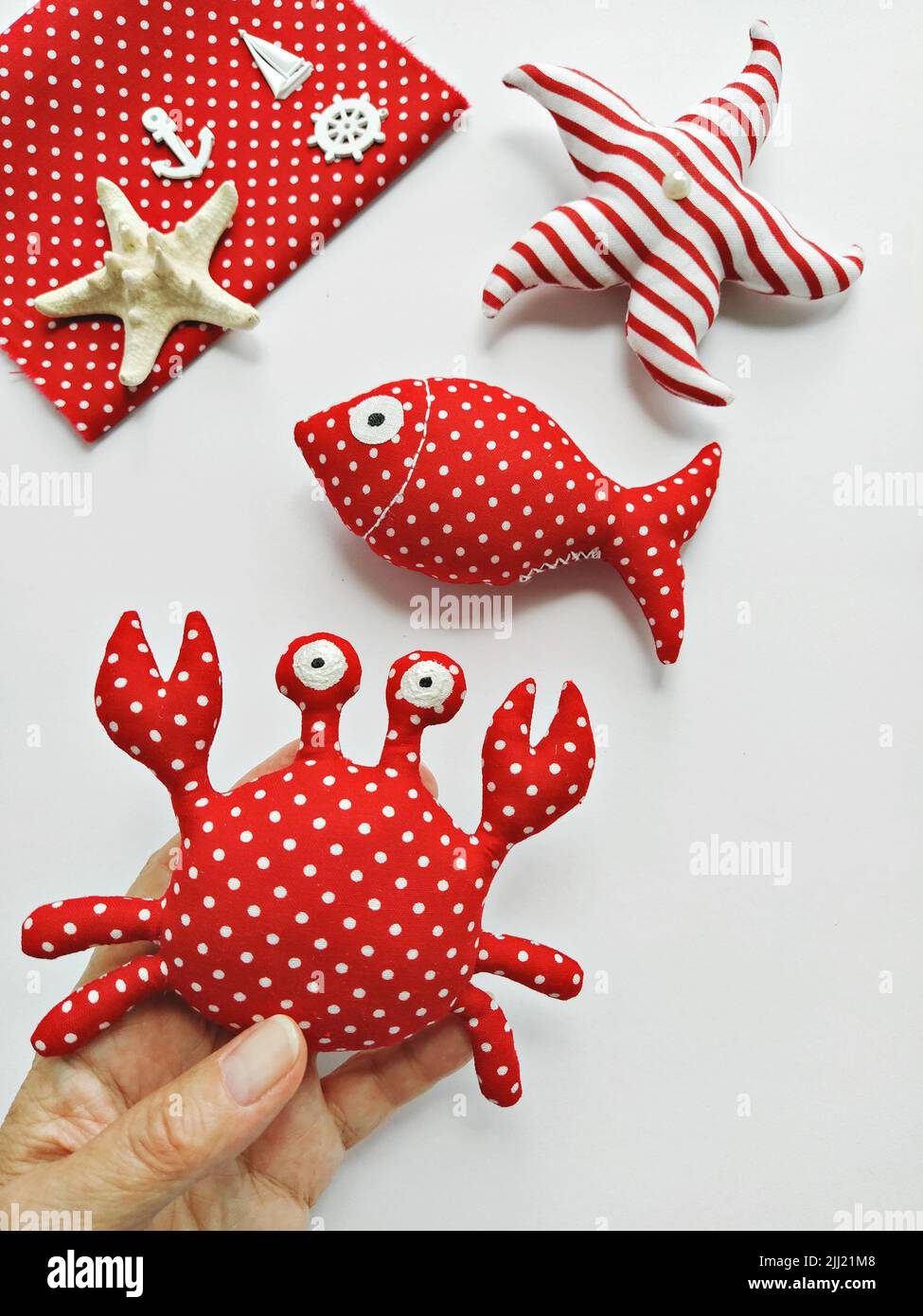 Handmade cartoon stuffed toys in hand, sea life octopus, crab, fish and seahorse. Toy crab, octopus, starfish, seahorse, and fish. DIY Stock Photo