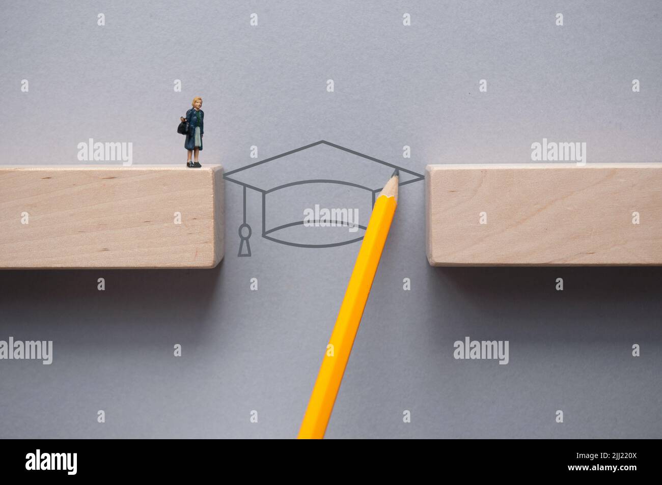 Pencil sketch with graduation hat bridging the gap between wooden blocks for female miniature figure to cross Stock Photo