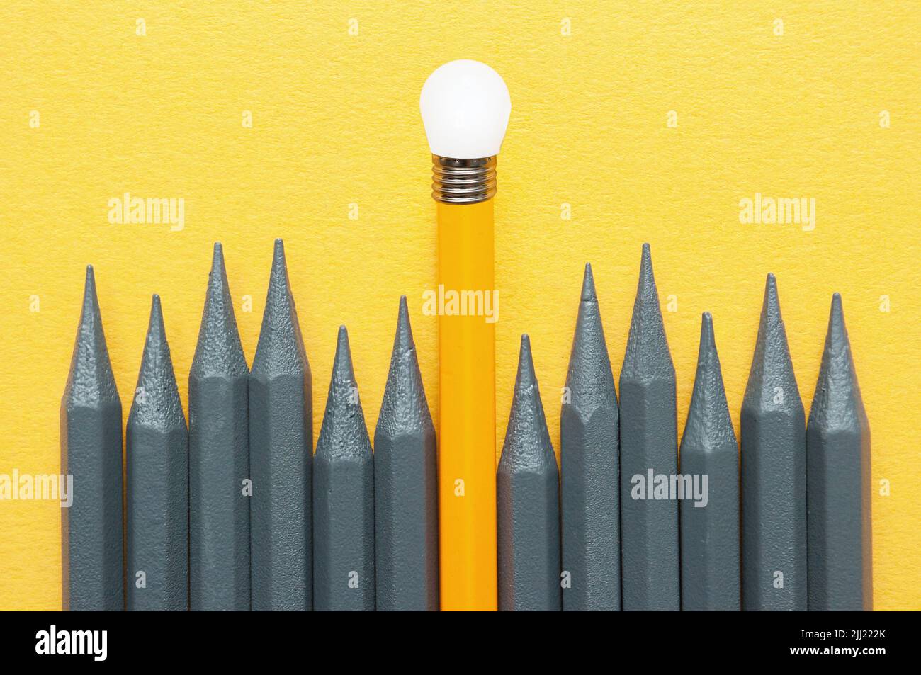 Orange pencil standing out amongst grey pencils with light bulb tip, unique ideas success concept Stock Photo