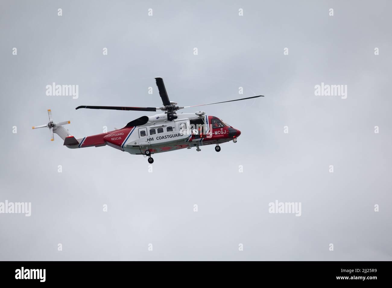 22.7.2022 A HM Coastguard Rescue Helicopter arriving at the scene of an accident in the village of Moelfre, Anglesey, North Wales UK - P Liggins/Alamy Live News Stock Photo