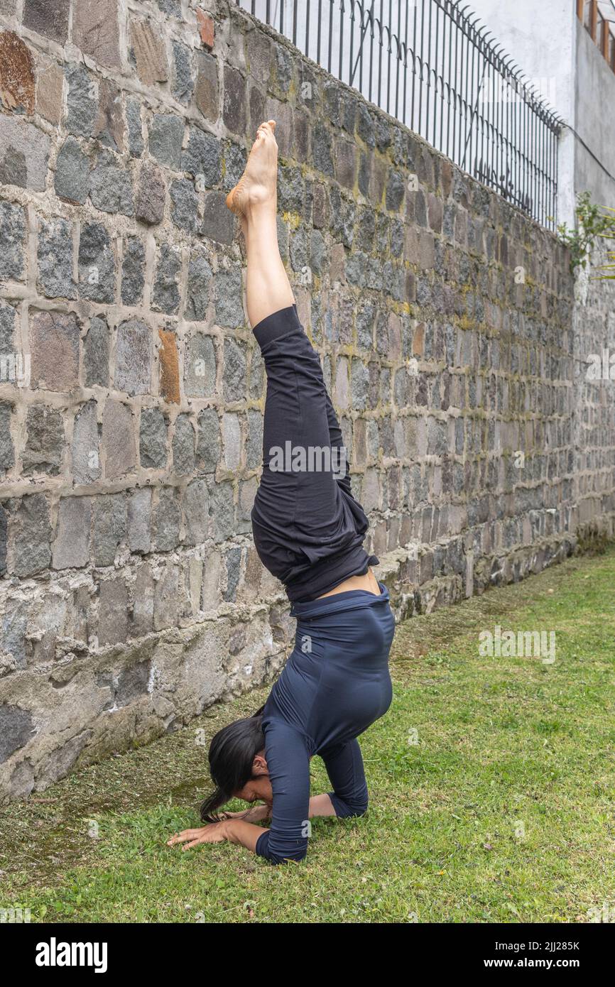 Young woman headstand in yoga salamba sirsasana position outdoors. Exercise and body care Stock Photo