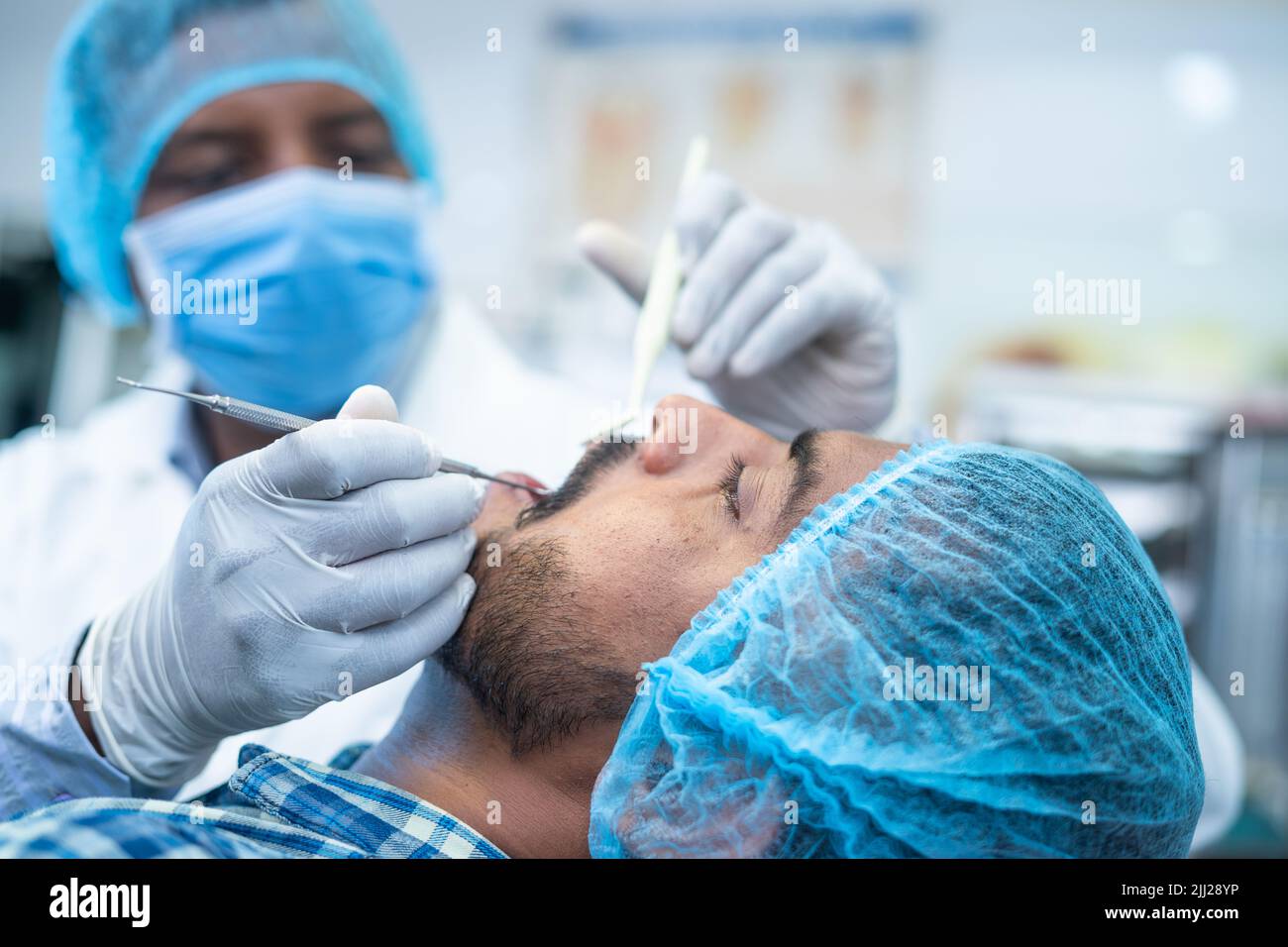 focus on patient Close up of dentist busy operating surgery at hospital - concept of dental care, toothache treatment and profesional occupation. Stock Photo