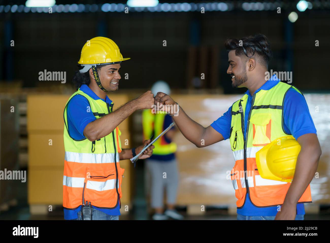 Happy Asian warehouse workers having fun and fist bumping during beginning start work in morning. Stock Photo