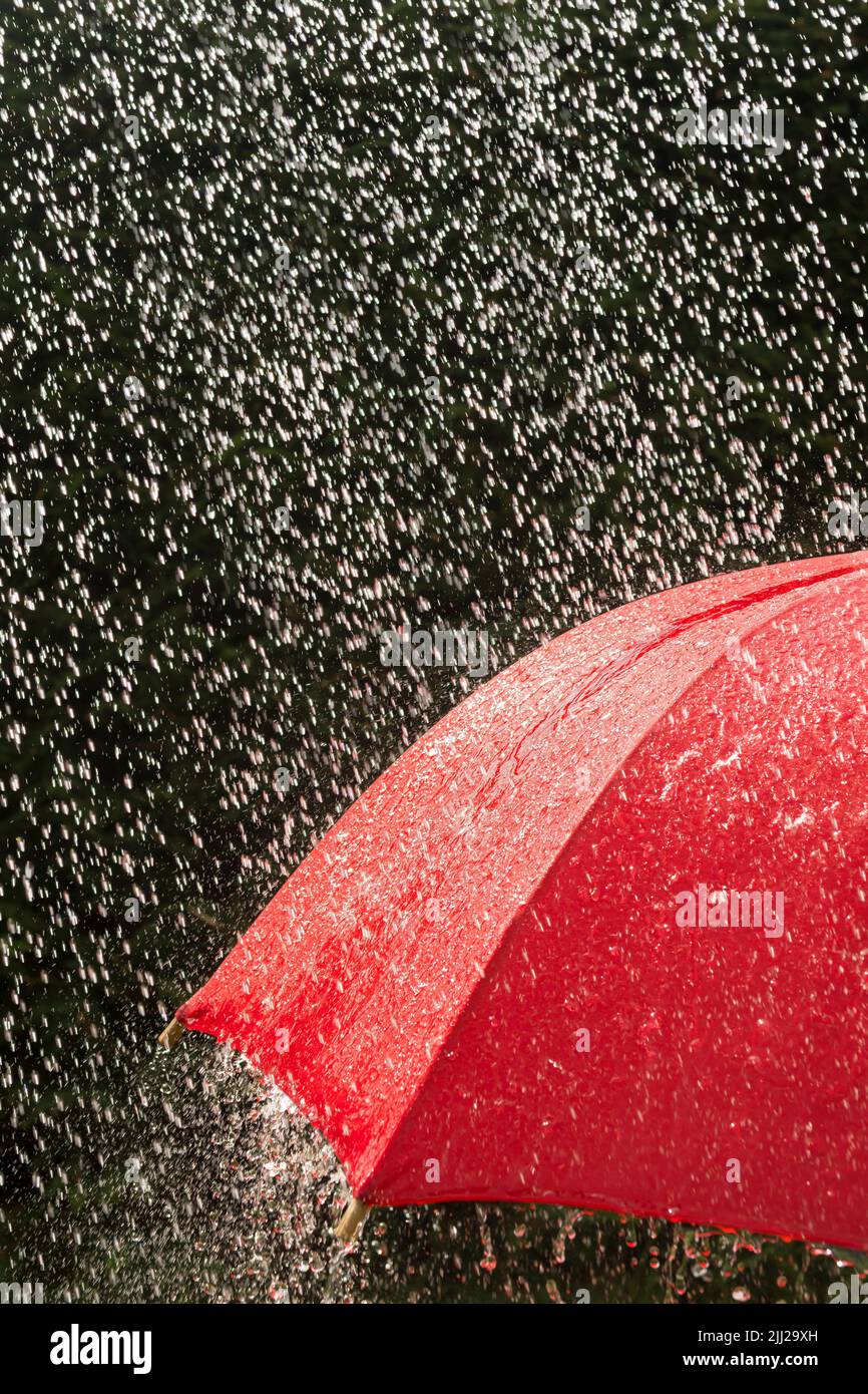 Red umbrella giving protection from heavy rain Stock Photo
