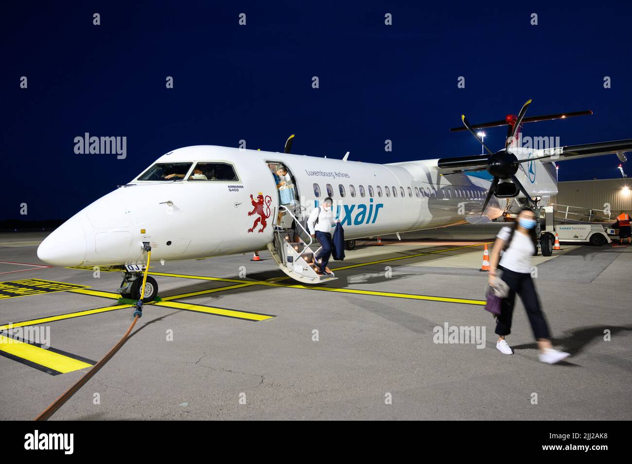 Passengers getting off a landed Luxair (Luxembourg Airlines) airplane (Bombardier Q400) at the Luxembourg Airport. Stock Photo