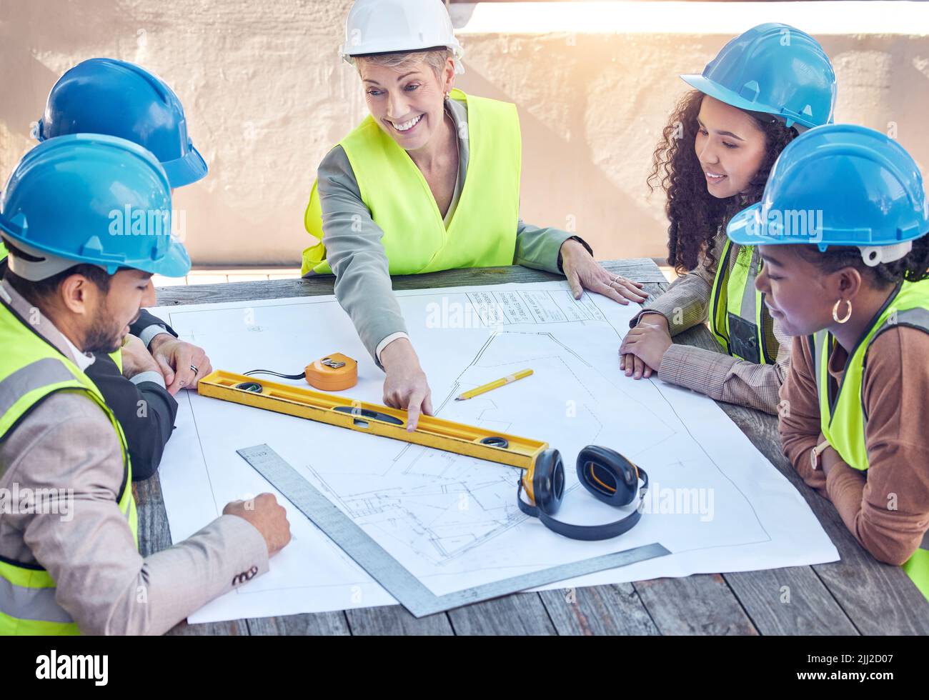 Making sure everything goes according to plan. a group of construction workers discussing blueprints while working on a building site. Stock Photo