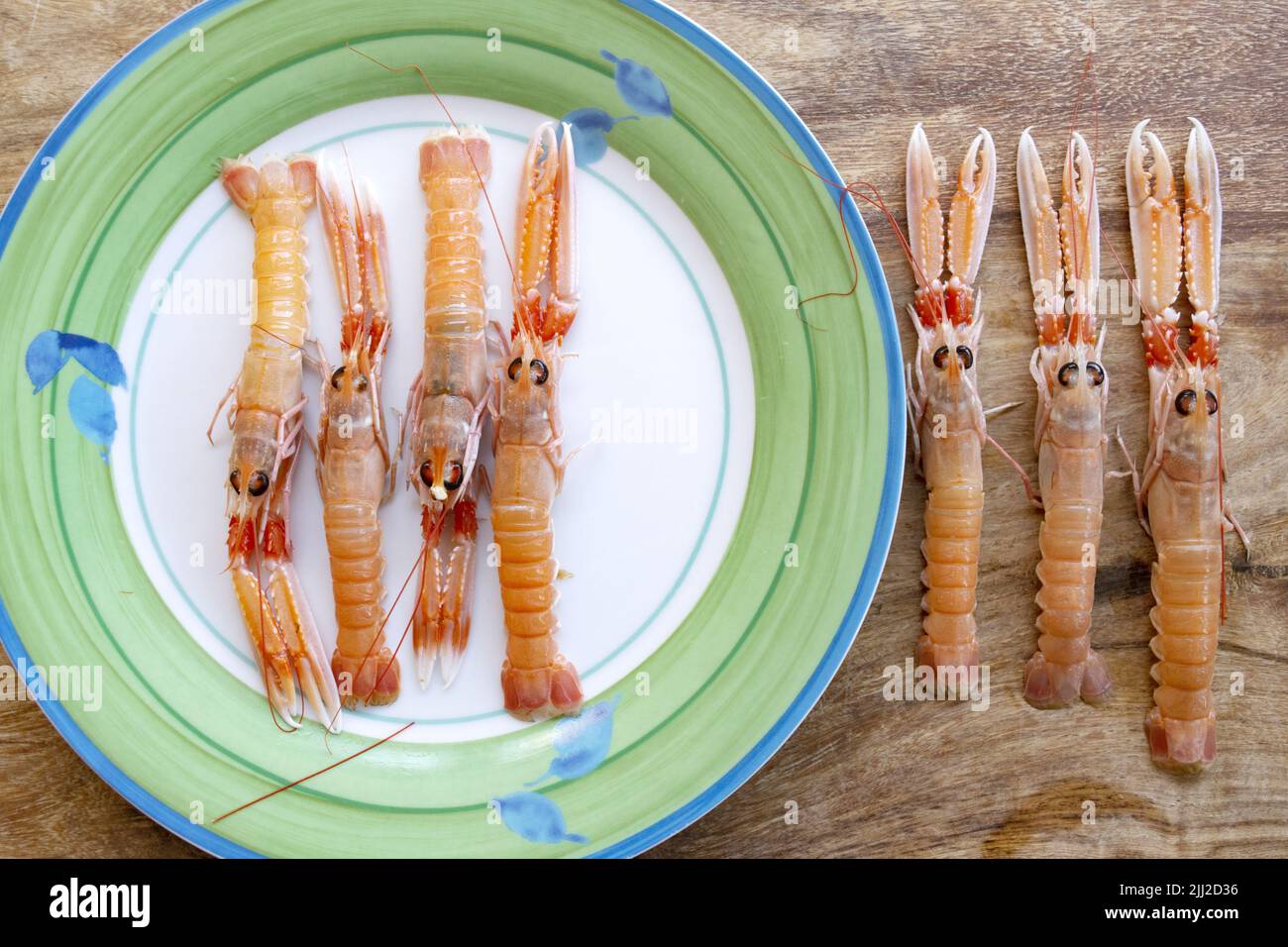 flat lay of fresh shrimps on a white dish and on a wooden table Stock Photo