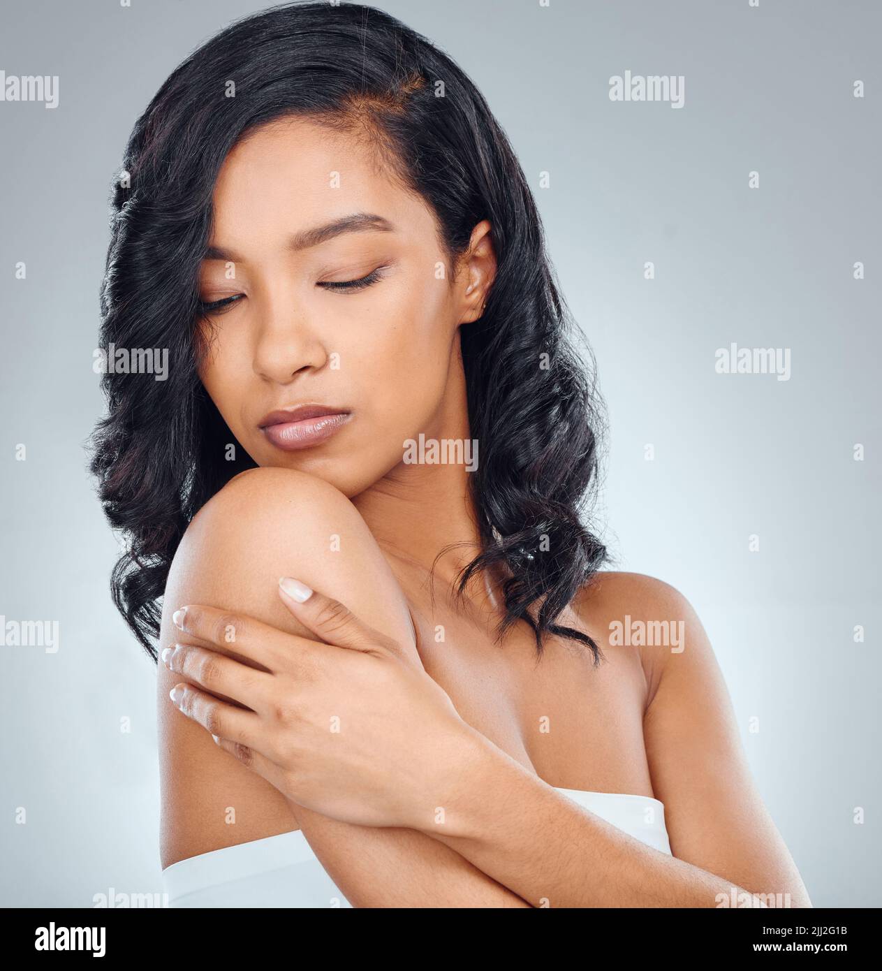 Moisturise your hair and body regularly. Studio shot of an attractive young woman posing against a grey background. Stock Photo