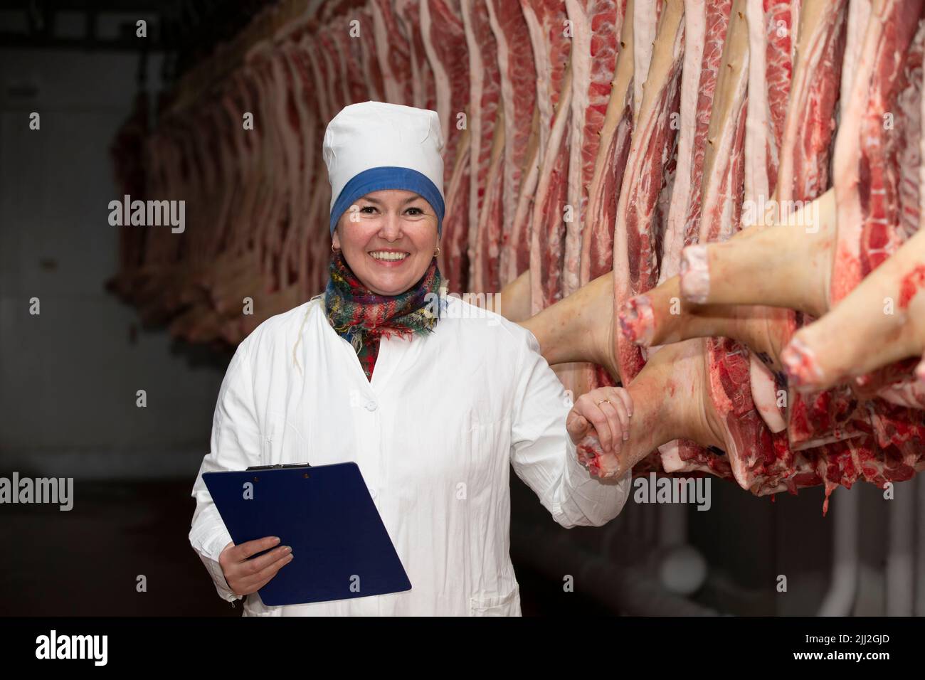 Meatpacking plant worker in front of butchered carcasses. Meat