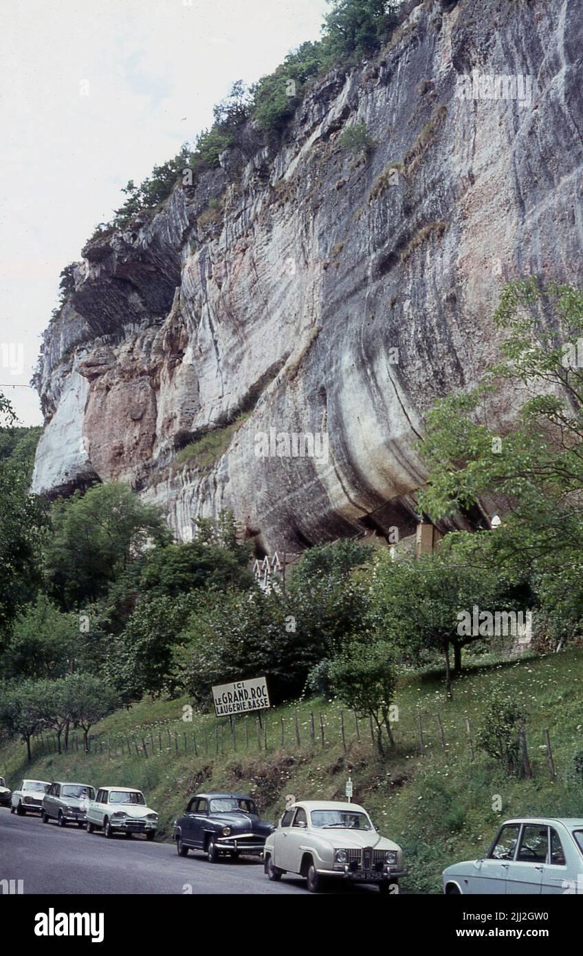 1980s, french cars of the era parked below Le Grand Roc, Laugerie-Basse, France. The entrance to the famous cave is halfway up the steep cliff face which overlooks the Vezere valley at Les Eyzies. Stock Photo
