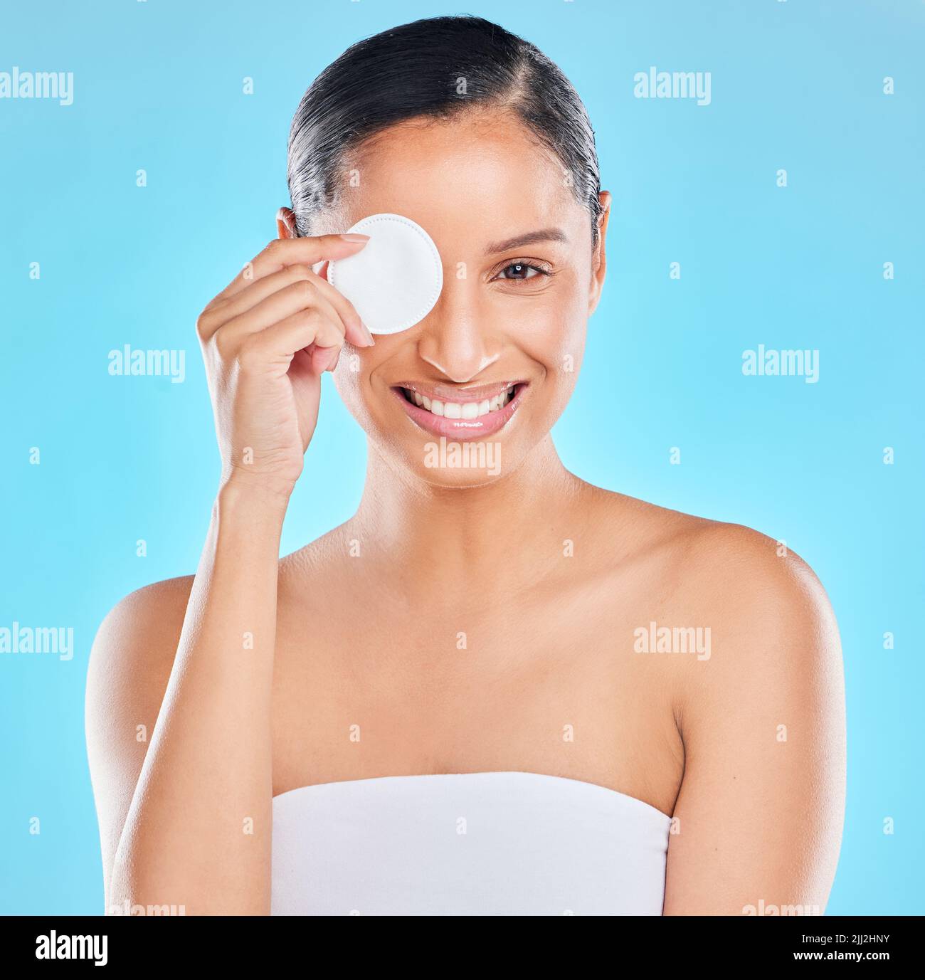 . Studio portrait of an attractive young woman exfoliating her face against a blue background. Stock Photo