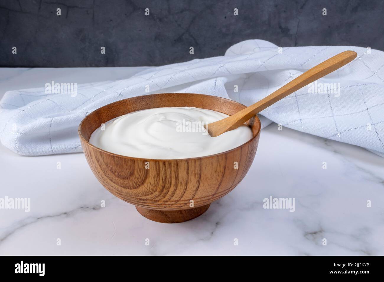 A portion of Greek yogurt in a wooden bowl ready to be served. Healthy food for dieting concept. Stock Photo