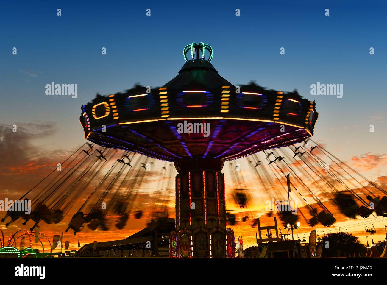 COSTA MESA, CALIFORNIA - 20 JUL 2022: Carnival swing ride with motion blur at the Orange County Fair with a beautiful sunset sky. Stock Photo