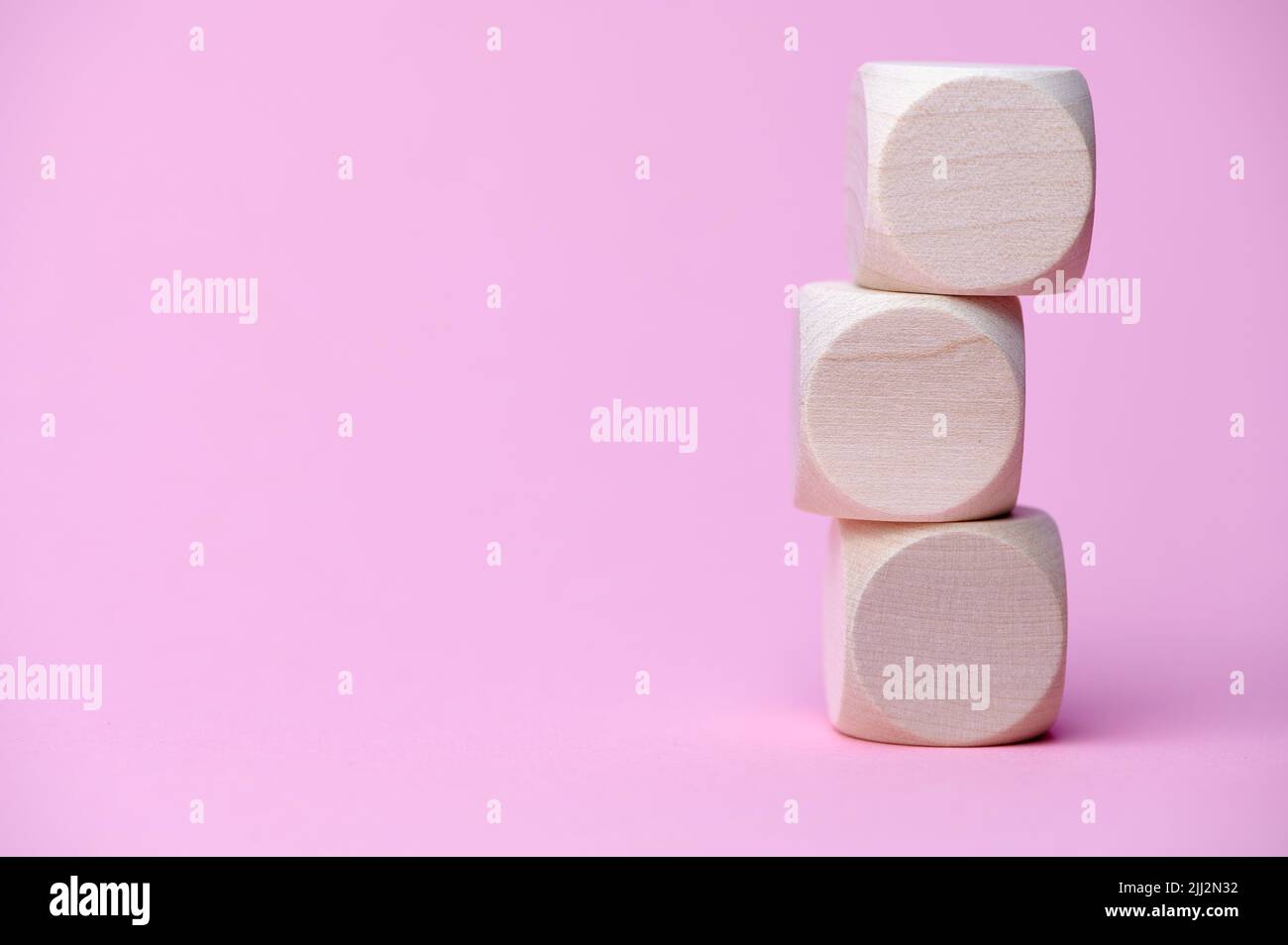 three wooden cubes on pink paper with copy space Stock Photo